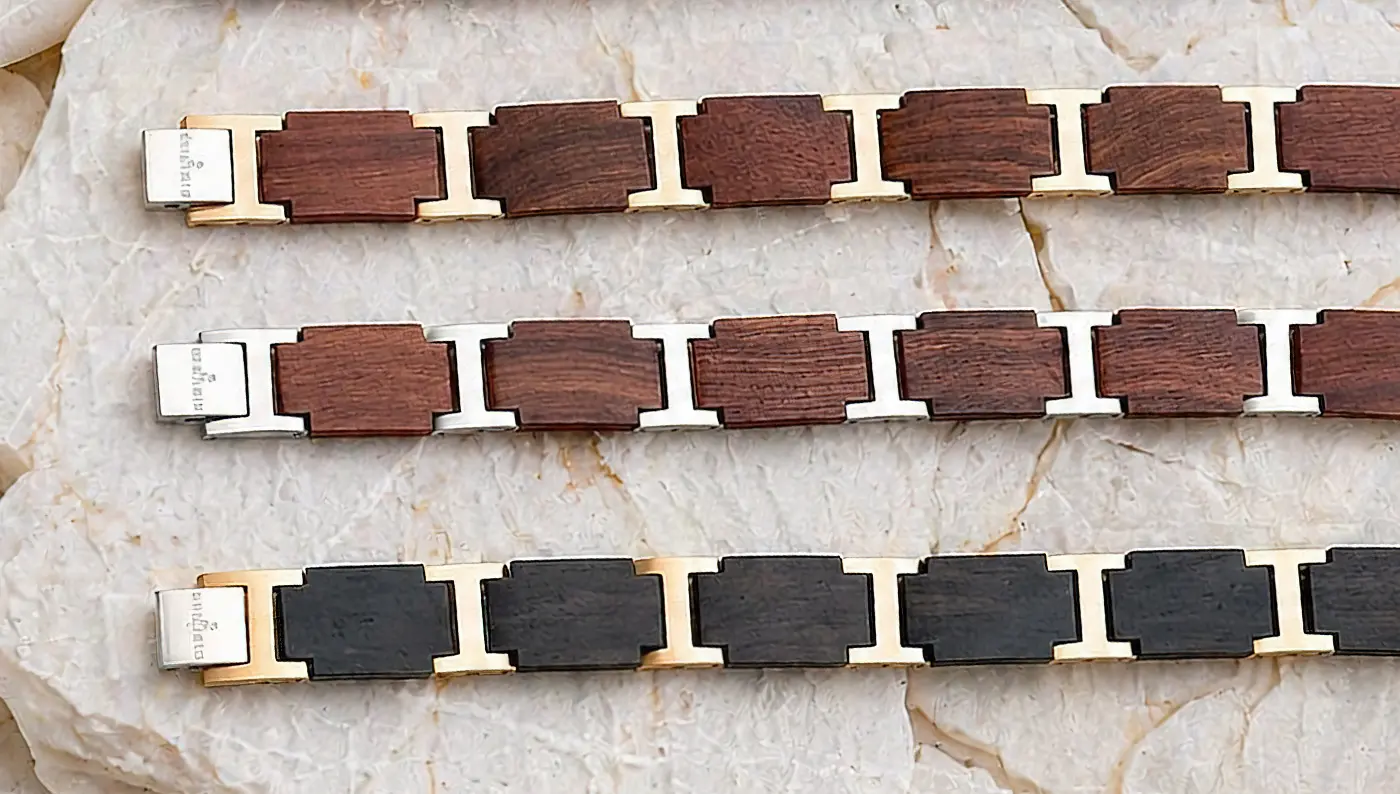 Bracelets en bois à maillons présentés à plat sur fond de pierre blanche